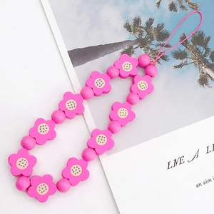 Close-up of bright pink flower wooden beads with blue dots for DIY phone strap charms