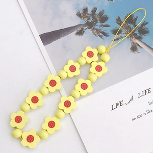 Detailed view of yellow flower beaded phone strap with polka dot center and wrist loop