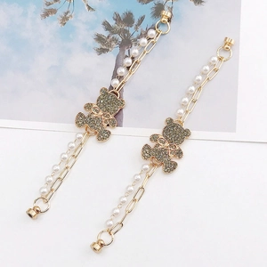 Detail of magnetic bear bracelet with gold chain, white pearls and sparkling rhinestones
