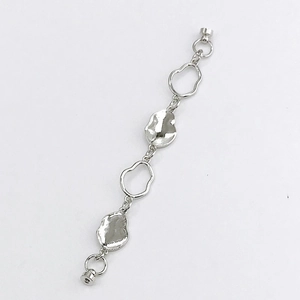 Close-up of silver irregular link chain with hammered metal discs and circular clasp
