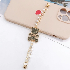 Detailed shot of pearl chain accessory featuring a crystal bear charm on a phone case