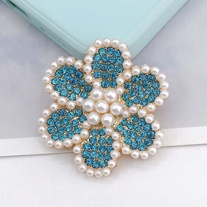 Vista detallada de flor de strass azul claro con perlas y base de metal dorado
