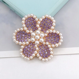 Vista detallada de un broche de flor con diamantes morados y perlas con baño de oro
