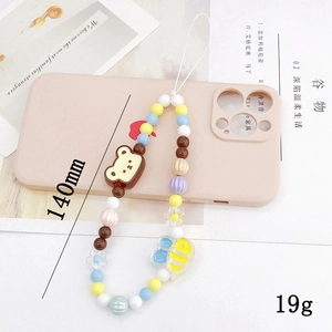 Détail d'une dragonne de téléphone perlée avec breloques d'ours et d'abeille sur coque rose