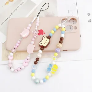 Détail de bijoux de téléphone faits main avec ours et étoiles colorés sur une coque rose