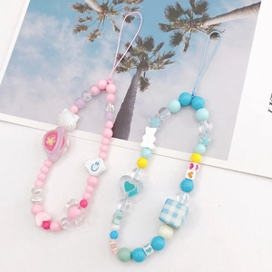 Flat lay of handmade colorful beaded phone lanyards with charms and checkered cubes