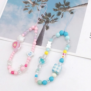 Detail of handmade beaded phone charms with colorful acrylic stars and checkered cubes