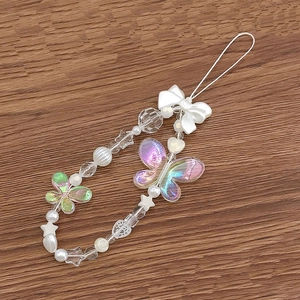 Beaded phone charm with iridescent butterfly pendants and white bows on wood background