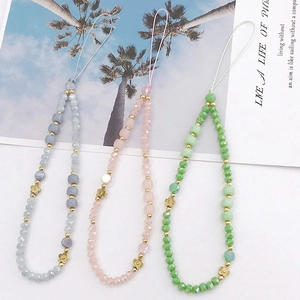 Detail of colorful crystal beaded phone lanyards with golden floral charms on decor card