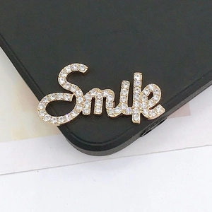 Macro detail of Smile letter charm with sparkling pavé zircons on gold metal base