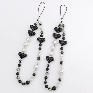Close-up of black and white beaded phone strap with resin hearts and striped beads