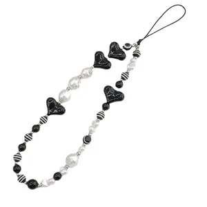 Handmade black and white beaded phone strap with acrylic hearts and striped beads on white backdrop