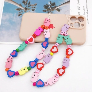 Handmade wooden bear phone charm with colorful beads and heart-shaped pendants on desk