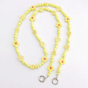 Detail view of yellow wooden beads with floral and heart patterns for phone lanyards
