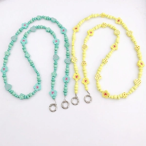 Detail of wooden flower and heart beaded phone charms in mint green and pale yellow