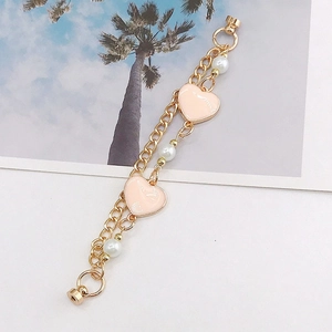 Close-up of golden metal chain with pink enamel hearts and white pearls charms
