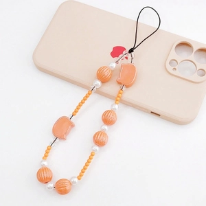 Detail of beaded phone strap with orange cat charm and striped beads on a phone case