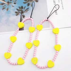 Close-up of beaded phone strap with pink round beads and yellow wooden heart charms