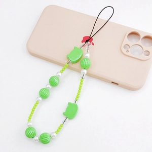 Close-up of green beaded phone strap with cat charm on a light pink case