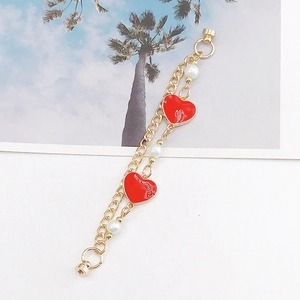 Detail view of gold chain with red enamel hearts and white pearls for DIY accessories