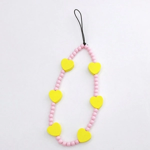 Close-up of pink round beads and yellow heart charm on a handmade phone wrist strap