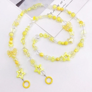 Dettaglio macro di catena di perline gialle con stelle, fiori e chiusura tonda in plastica