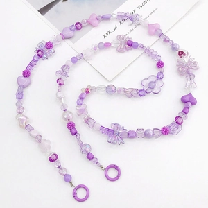 Dettaglio macro del cinturino in perline viola con ciondoli a cuore e fiori