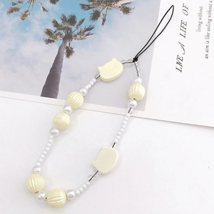 Detail of pearlescent beaded phone strap with cream cat charms and ribbed pumpkin beads