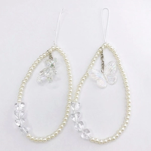 Detail of beaded phone charms with laser bear, butterfly pendants and white faux pearls
