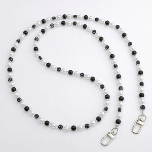 Detail of beaded phone strap with black and white pearls, smiley faces, and silver clasps