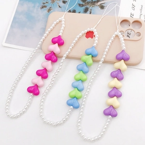 Three colorful acrylic heart-shaped beaded phone charms on a soft pink background