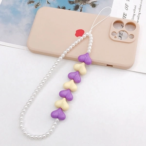 Beaded heart phone charm with white pearls and purple acrylic hearts on a beige background