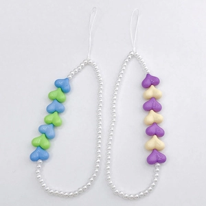 Detailed view of handmade heart shaped acrylic beads and faux pearls phone charms