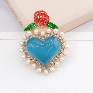 Détail d'un pendentif cœur bleu avec perles blanches et petite breloque de rose rouge