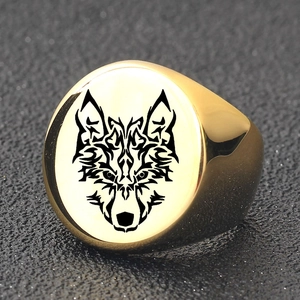 Gros plan sur une bague chevalière dorée pour homme avec gravure de tête de loup