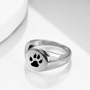 Macro shot of circular laser engraved pet paw print on polished stainless steel ring