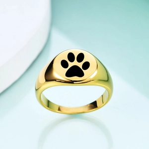 Detail of a polished gold signet ring featuring a black cat paw laser engraving