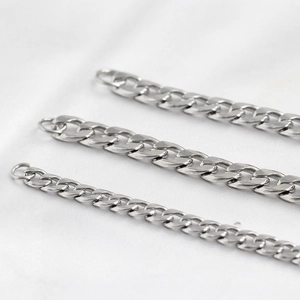 Détail de chaînes à mailles gourmette en acier inoxydable sur fond de satin blanc