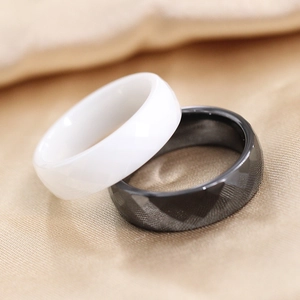 Detailweergave van de zwarte facet- en witte gladde keramische ringen op zijden achtergrond
