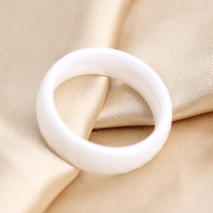 Macro-opname van een witte keramische ring op luxueus champagnekleurig satijn