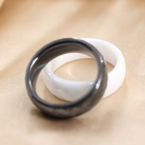 Detailweergave van zwarte en witte keramische ringen op elegante champagne zijden stof