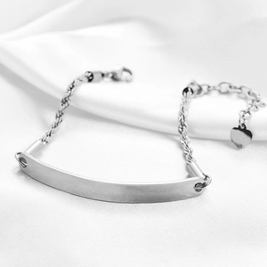 Macro detail of silver stainless steel ID bracelet with rope chain and heart charm
