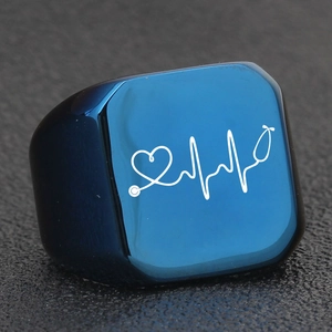 Macro shot of navy blue stainless steel ring with white heartbeat and stethoscope design