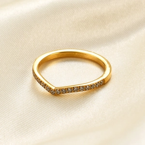 Macro shot of 2MM gold V-shaped ring with pavé clear zircons on cream silk fabric