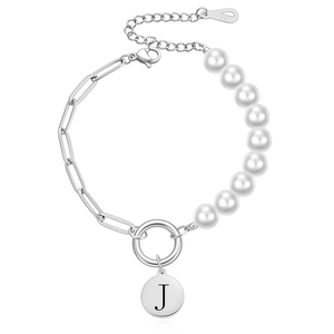 Detail van roestvrijstalen armband met witte parels en een hanger met de letter J