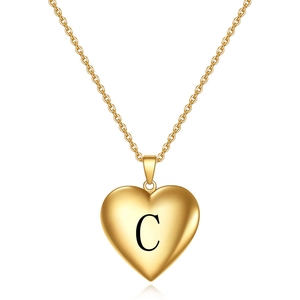 Vue détaillée d'un pendentif cœur doré avec une gravure noire de la lettre C sur le devant