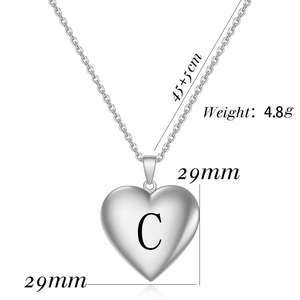 Macro-opname van zilveren hart medaillon met gegraveerde letter C op een ketting