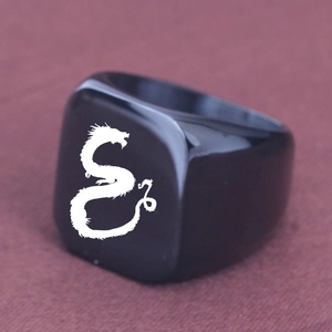 Vista macro di un anello quadrato in acciaio nero con motivo a drago bianco inciso