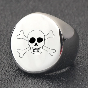 Macro shot of silver stainless steel ring featuring a laser engraved skull on circular surface