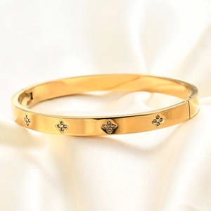 Macro-opname van een gouden scharnierarmband met bloemmotieven en zirkonia-accenten